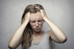 Woman suffers from hormonal migraines shown holding hands up to head